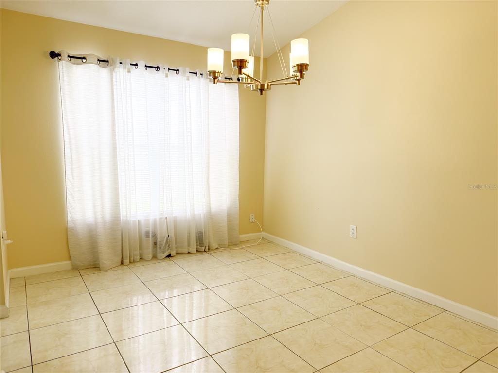 A dining room with beige walls, tile flooring, a chandelier, and floor-length white curtains — 3245 WHOOPING CRANE RUN, KISSIMMEE, FL