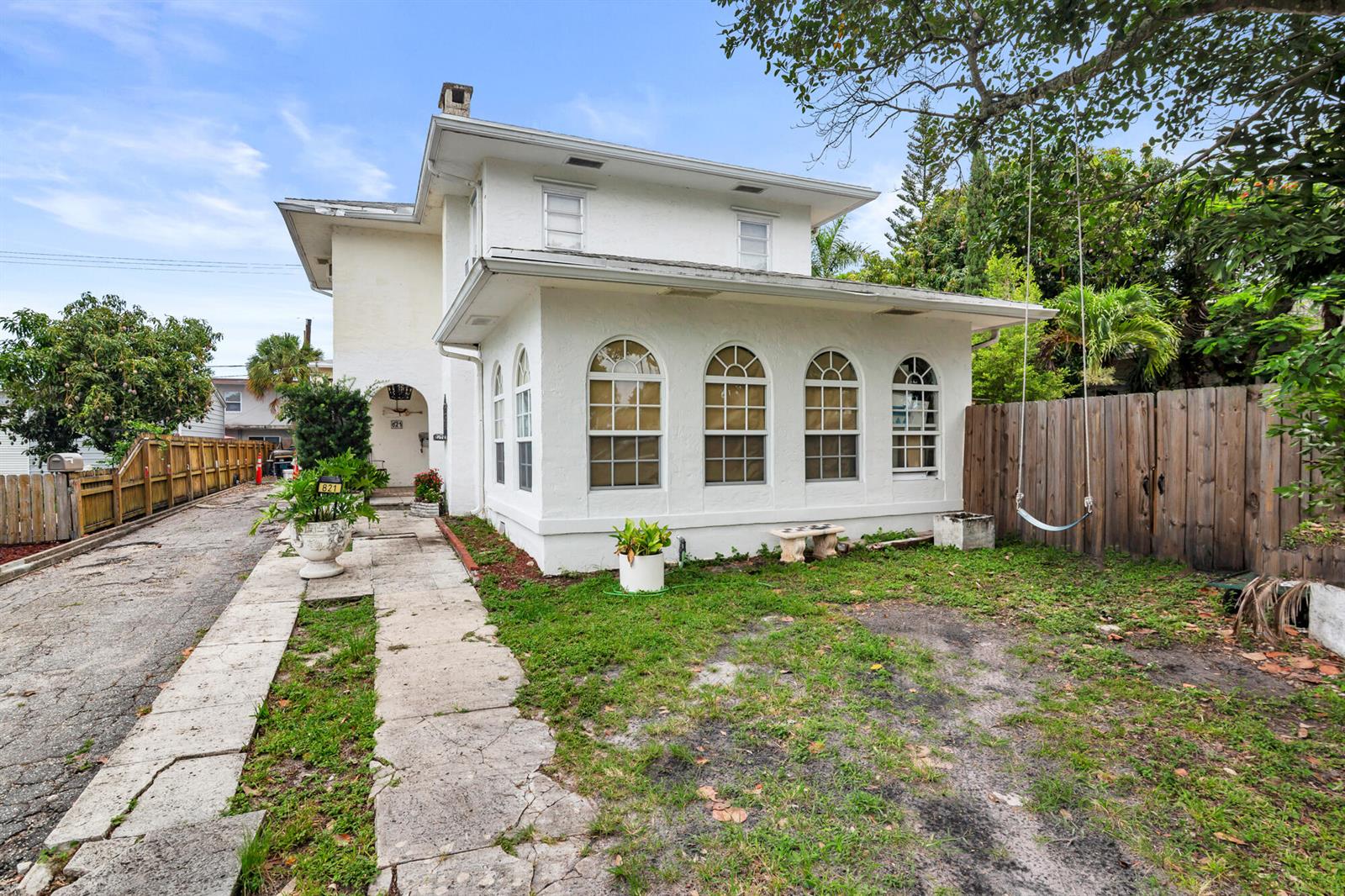 A two-story white stucco house features arched windows and a concrete walkway in the yard — 821 Omar Road, West Palm Beach FL 33405, WEST PALM BEACH, FL