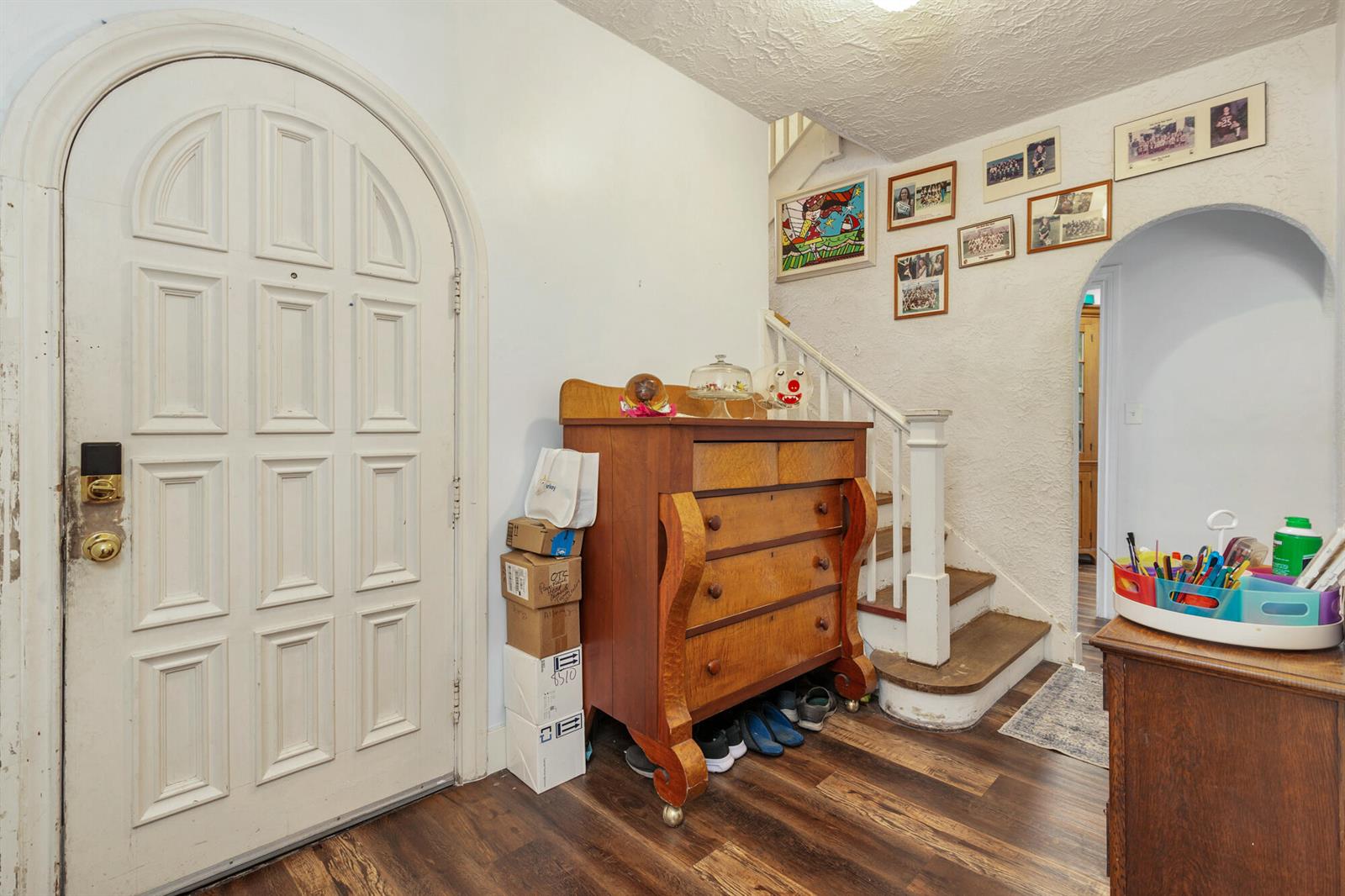 An entryway features a white arched door, a wooden dresser, and stairs leading upward — 821 Omar Road, West Palm Beach FL 33405, WEST PALM BEACH, FL