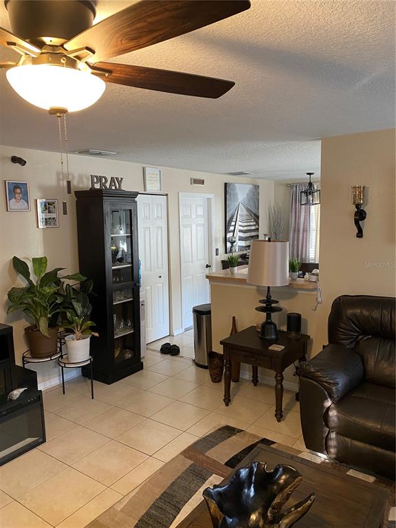 A living room features tile flooring, a ceiling fan, a dark cabinet, and a recliner — 10328 SUMMERVIEW CIRCLE, RIVERVIEW, FL