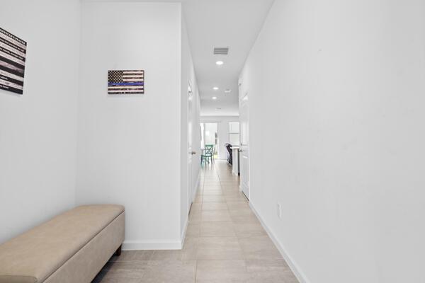 A hallway with light tile flooring leads from a foyer toward a distant living area — 419 Salisbury Circle, Fort Pierce FL 34982, FORT PIERCE, FL