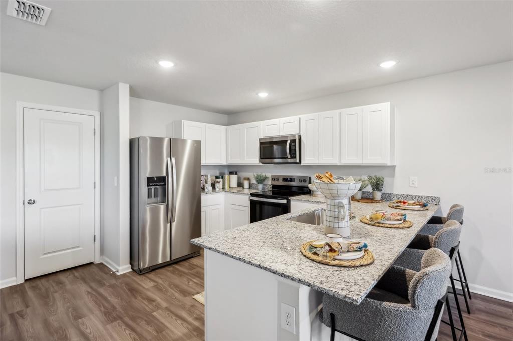 A kitchen with white cabinets, granite countertops, stainless steel appliances, and a breakfast bar island — 5103 LA SALLE STREET, FORT PIERCE, FL