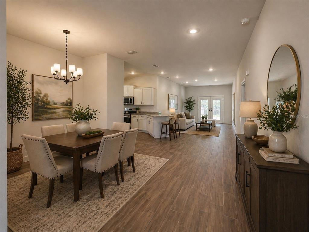 An open-concept dining area and living room with wood-look tile flooring and white cabinetry — 12992 KENT BRADLEY STREET, DADE CITY, FL