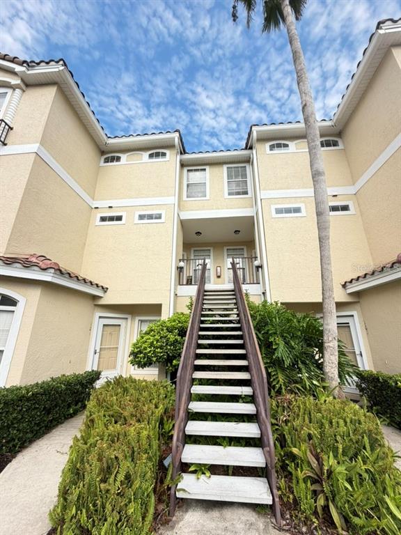 An exterior view of a multi-story apartment building with a central staircase leading to balconies — 673 SANDY NECK LANE UNIT 201, ALTAMONTE SPRINGS, FL