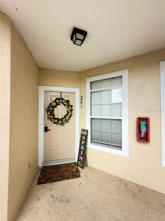 A beige front door with a lemon wreath and a spring sign on a porch — 673 SANDY NECK LANE UNIT 201, ALTAMONTE SPRINGS, FL