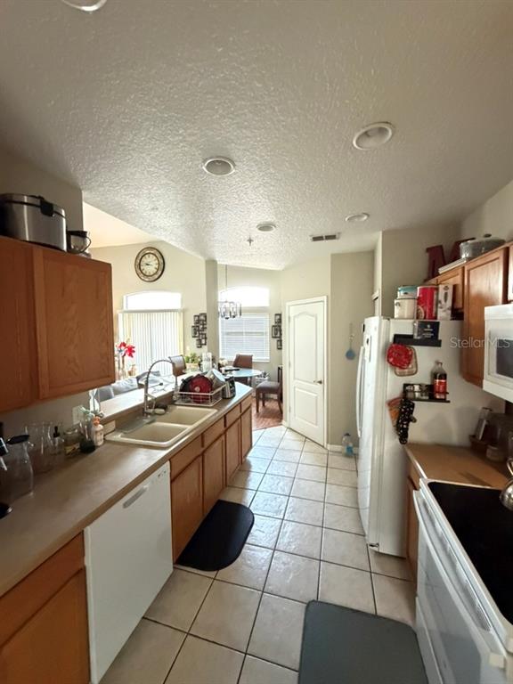 A kitchen with wood cabinets, white appliances, and tile flooring overlooks a dining area — 673 SANDY NECK LANE UNIT 201, ALTAMONTE SPRINGS, FL