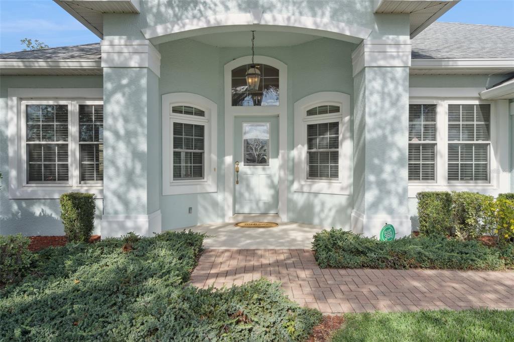 The front entrance of a light blue house features a paved walkway and landscaping — 2925 DAYTON DRIVE, WINTER HAVEN, FL