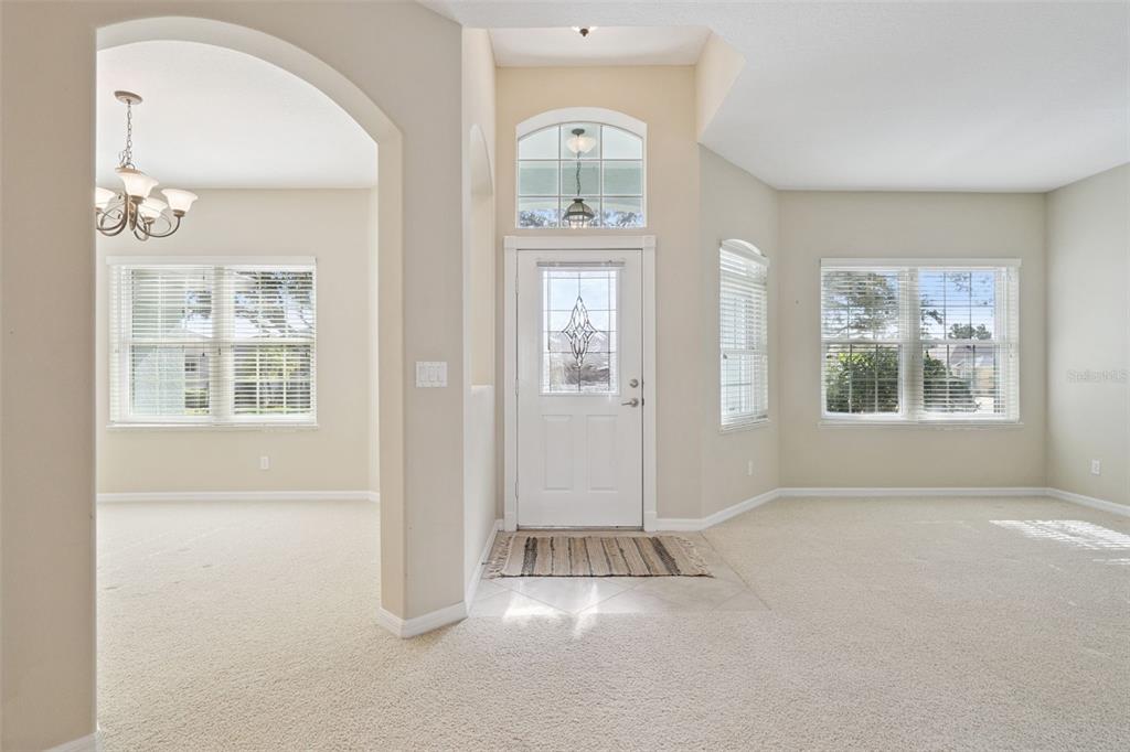 A bright entryway features a front door with a transom window and beige carpeting — 2925 DAYTON DRIVE, WINTER HAVEN, FL