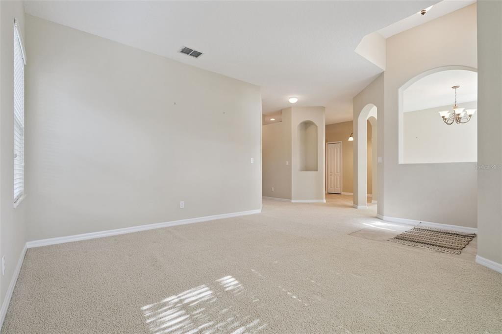 A formal living room features beige furniture, a patterned area rug, and arched wall niches — 2925 DAYTON DRIVE, WINTER HAVEN, FL