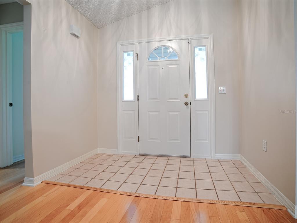 An entryway features a white front door with sidelights, tile flooring, and hardwood transition — 419 RANCHWOOD DRIVE, LEESBURG, FL