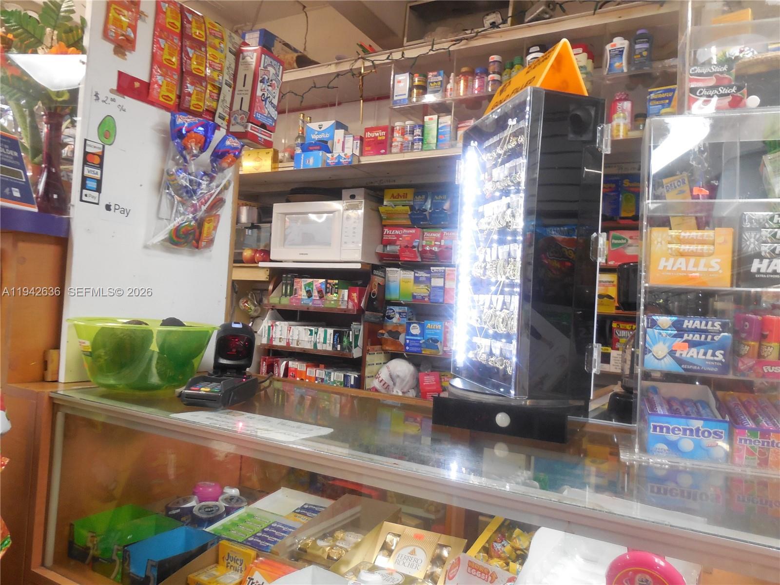 A retail store counter displays various snacks, medicines, and jewelry items for sale — NW 12th Ave, Miami FL 33128, MIAMI, FL