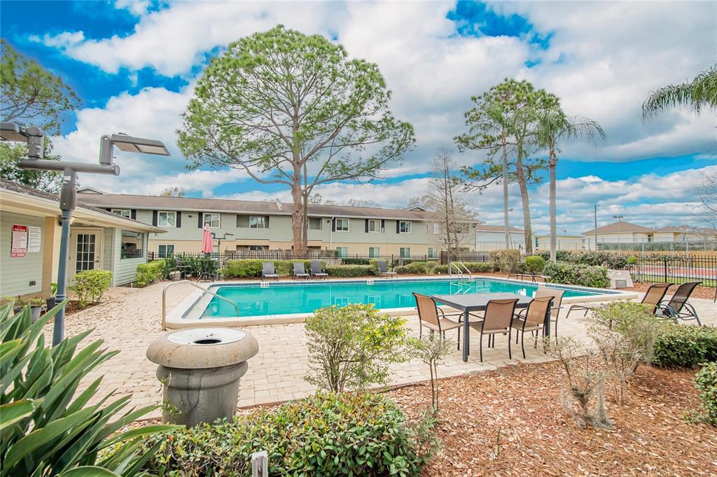 An outdoor swimming pool area features a patio with dining furniture and a large tree — 202 RED MAPLE PLACE UNIT 202, BRANDON, FL