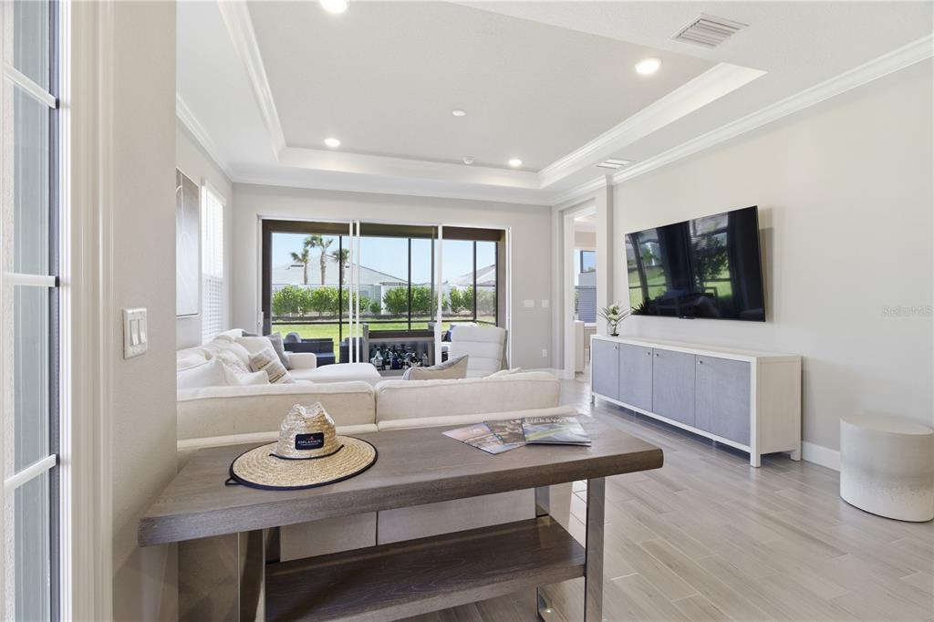A living room features a white sectional sofa, a console table, and a wall-mounted television — 16255 SAN DONATO PLACE, BRADENTON, FL
