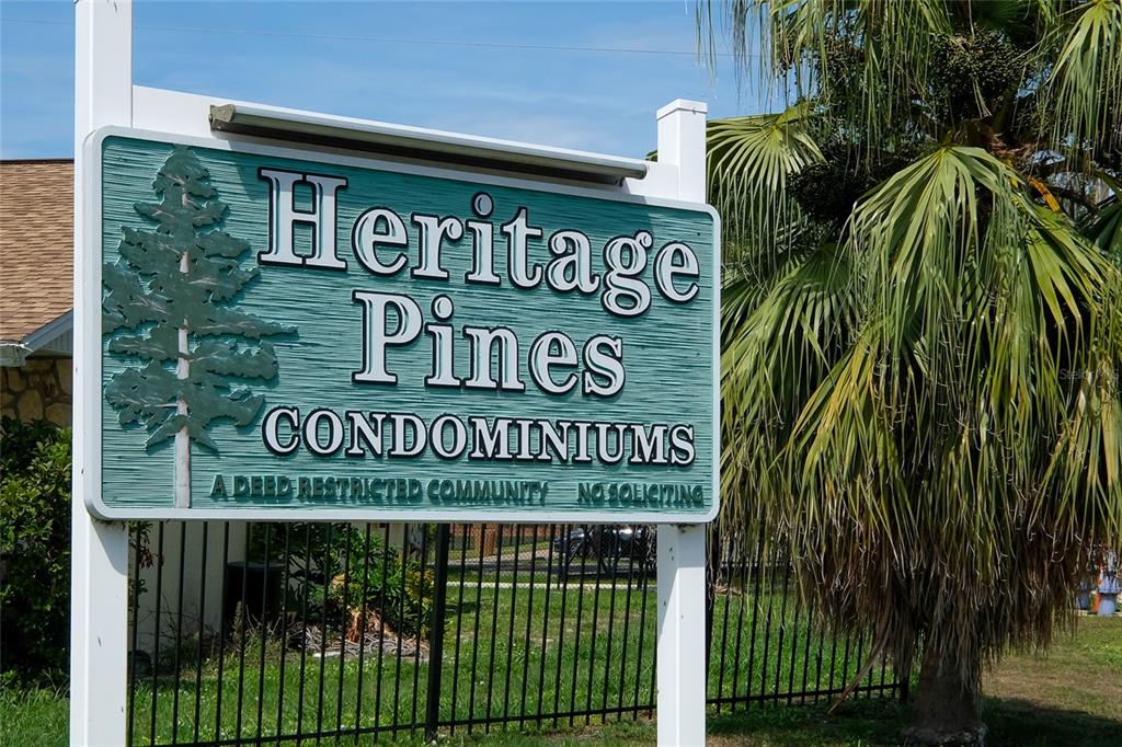 A sign for Heritage Pines Condominiums stands in front of a black metal fence — 4304 78TH STREET W UNIT 54, BRADENTON, FL