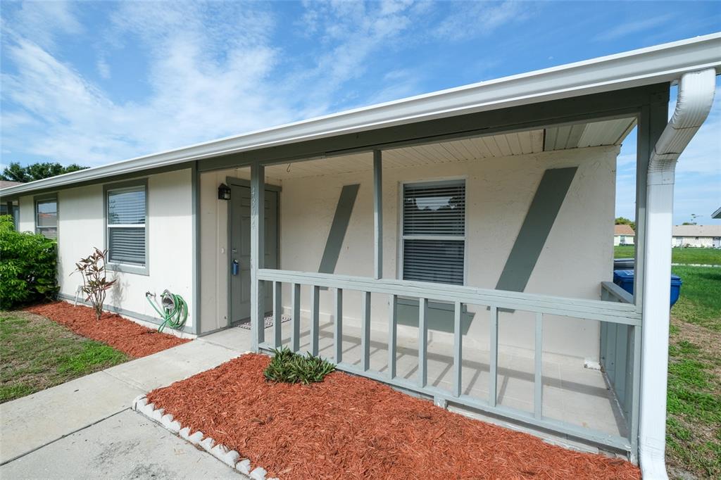 A single-story home exterior features a covered front porch with a gray railing and siding — 4304 78TH STREET W UNIT 54, BRADENTON, FL