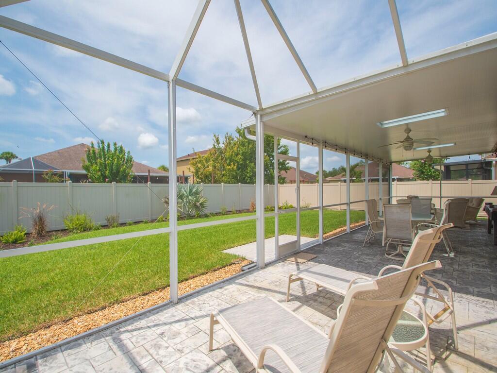 A screened-in patio with a concrete floor, lounge chairs, and a view of the backyard — 10105 Verona Manor, Vero Beach FL 32966, VERO BEACH, FL