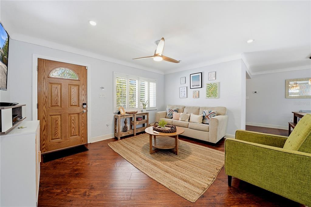 A living room features wood flooring, a beige sofa, a green armchair, and a front door — 955 INDIAN ROCKS ROAD S, LARGO, FL