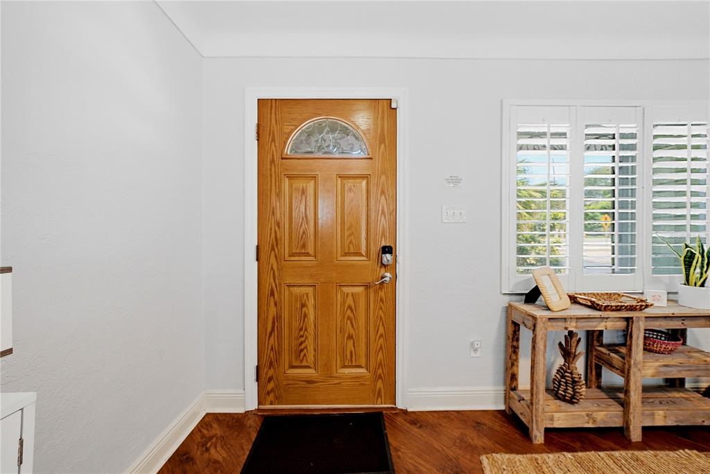 An entryway features a wood front door, light-colored walls, and a rustic wooden console table — 955 INDIAN ROCKS ROAD S, LARGO, FL