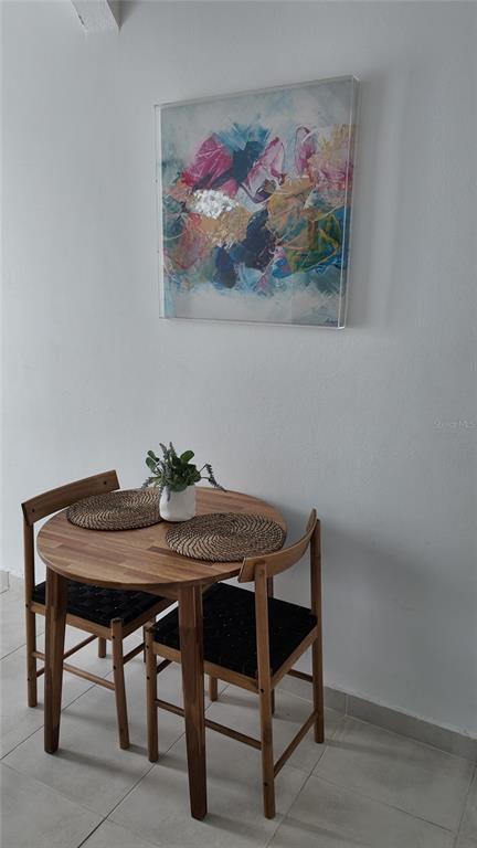 A small wooden dining table with two chairs sits against a wall under abstract art — 73 CALLE TAPIA UNIT 2, SAN JUAN, PR