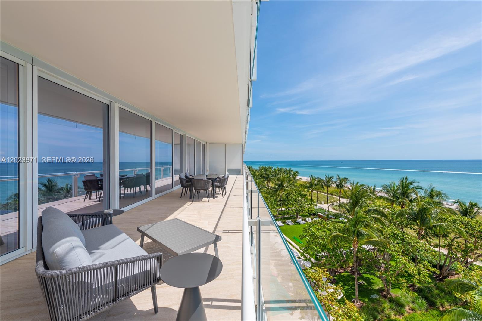 A high-rise balcony features outdoor furniture, glass railings, and a view of the ocean — 9001 Collins Ave # 509, Surfside FL 33154, SURFSIDE, FL