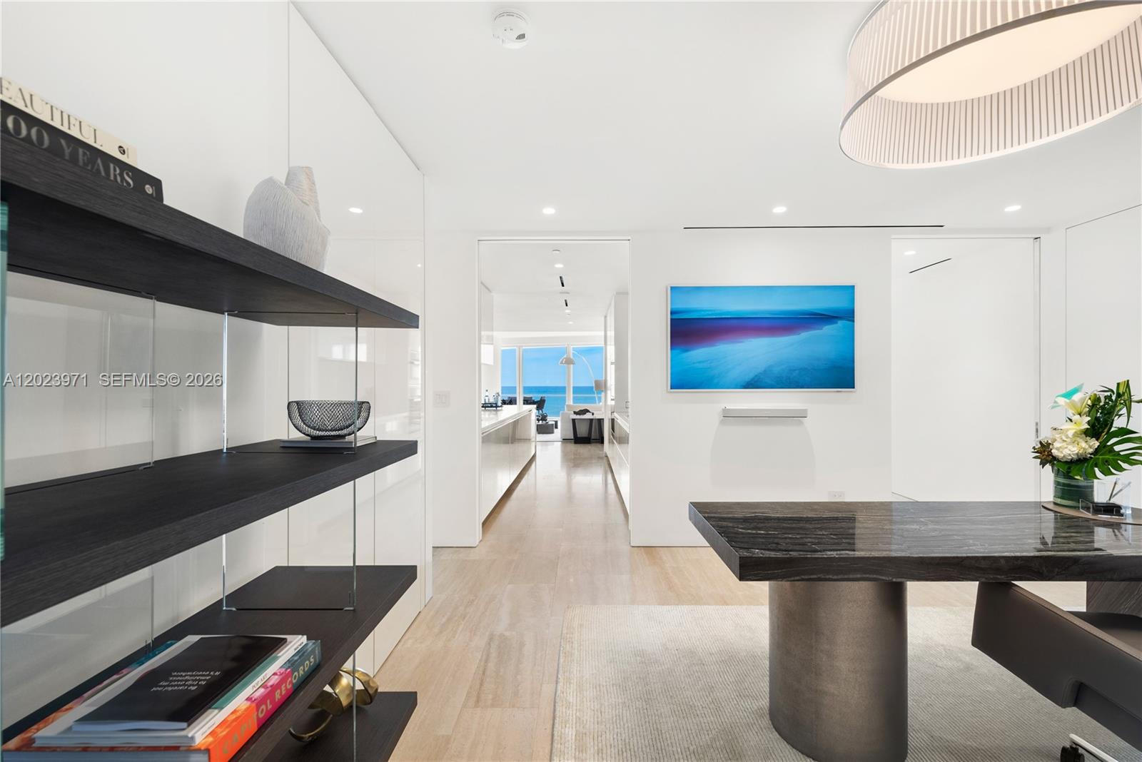 A modern dining area features a dark stone table, open shelving, and a hallway view — 9001 Collins Ave # 509, Surfside FL 33154, SURFSIDE, FL