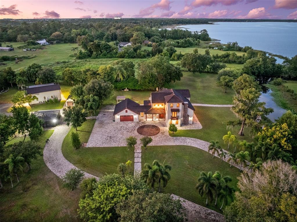 An aerial view of a large house with a circular driveway, pool, and waterfront property — 11205 TINDALL ROAD, ORLANDO, FL