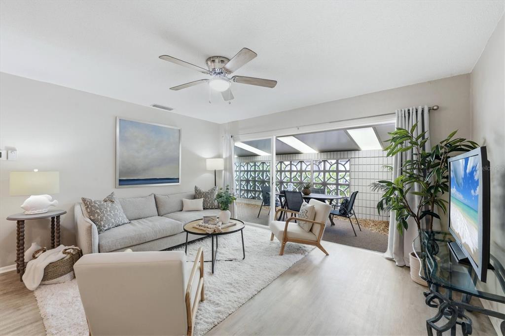 A living room features a gray sofa, white armchairs, a ceiling fan, and a patio — 405 MENENDEZ STREET, VENICE, FL