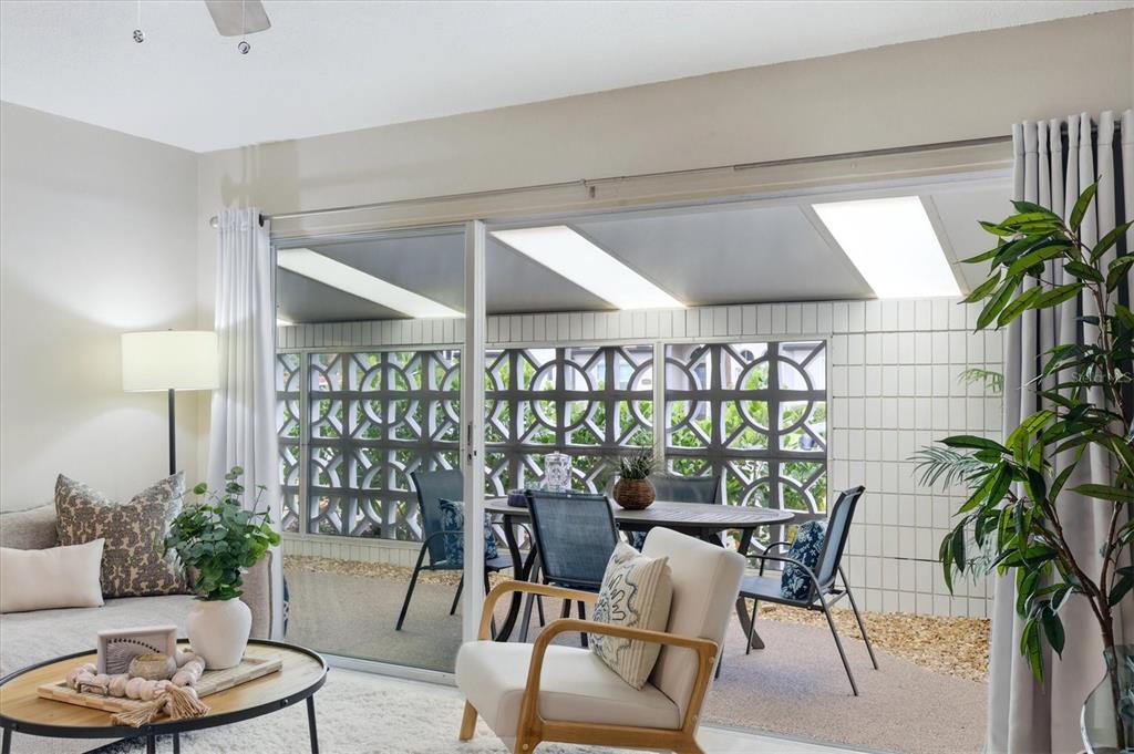 A living room looks out through a sliding glass door to a screened-in patio area — 405 MENENDEZ STREET, VENICE, FL