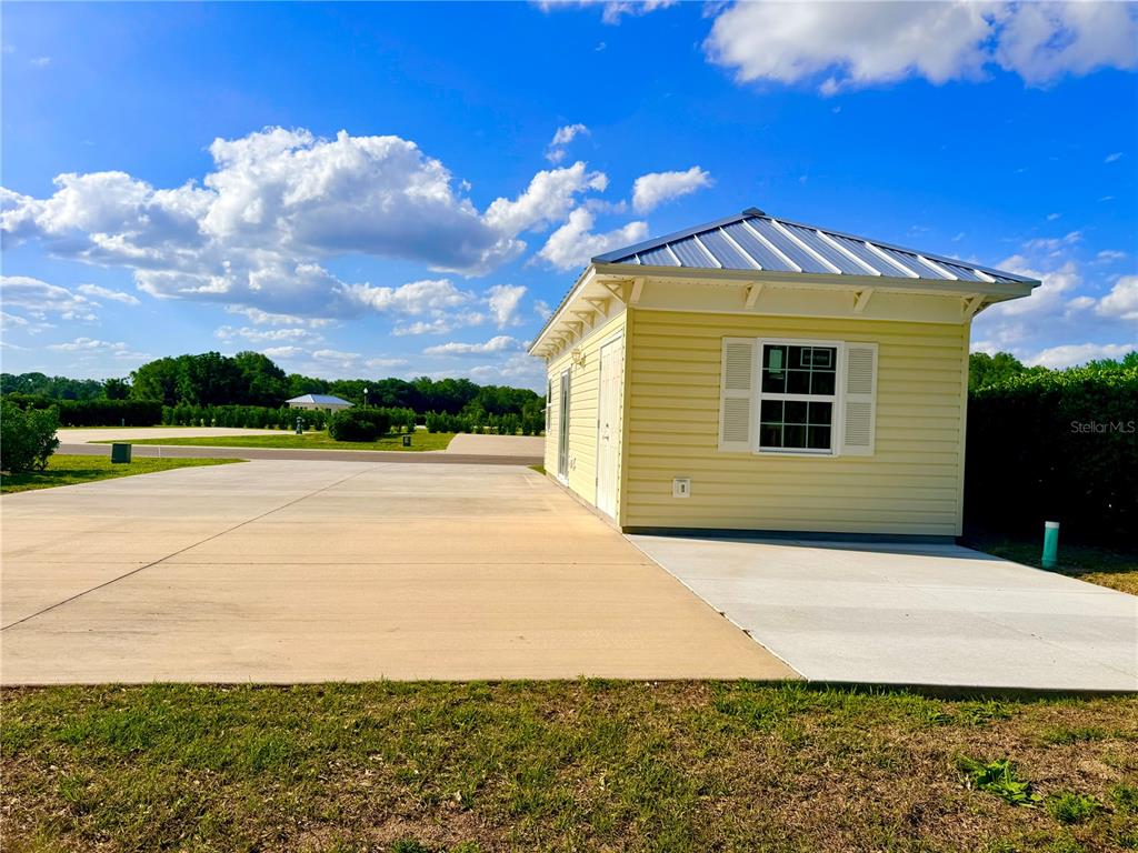 A yellow shed with a metal roof sits on a concrete pad under a sky — 4885 SE 92ND BOULEVARD, WEBSTER, FL