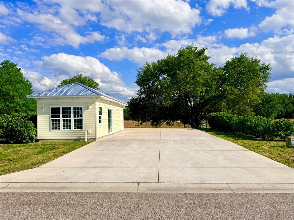 A light yellow detached garage with a metal roof sits beside a large concrete driveway — 4885 SE 92ND BOULEVARD, WEBSTER, FL