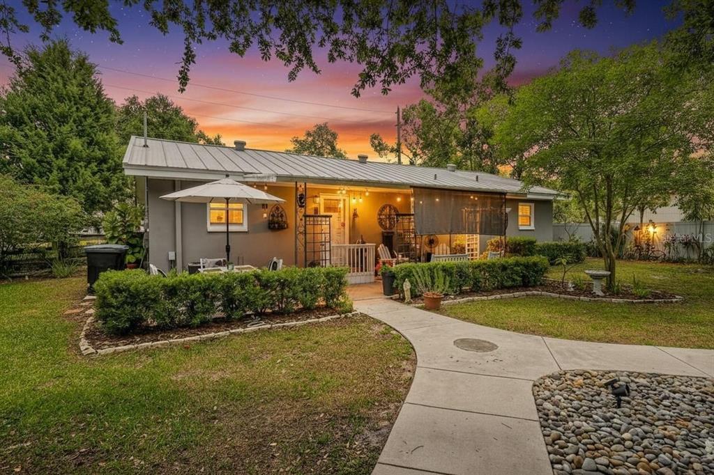 A single-story house with a metal roof, patio, and landscaped yard at sunset — 175 RIVIERE ROAD, PALM HARBOR, FL