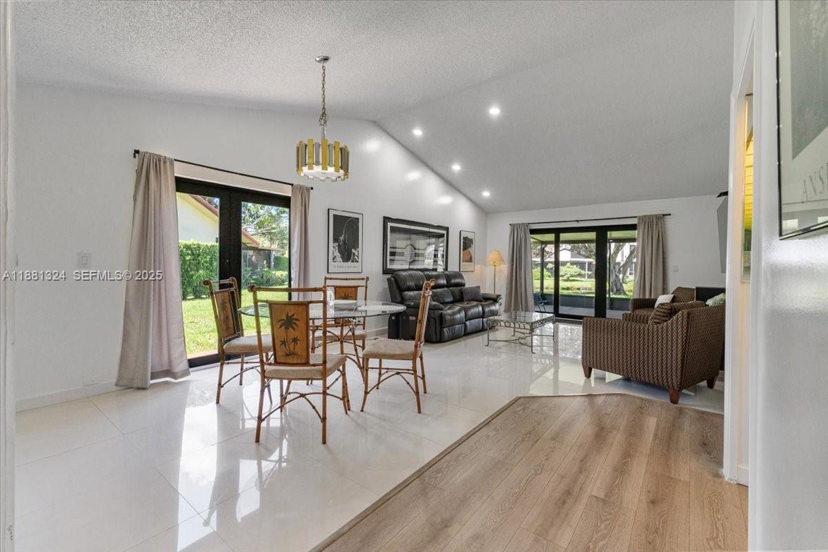 A bright living and dining area features white tile floors, vaulted ceilings, and glass doors — 16273 Laurel Dr # 7, Weston FL 33326, WESTON, FL