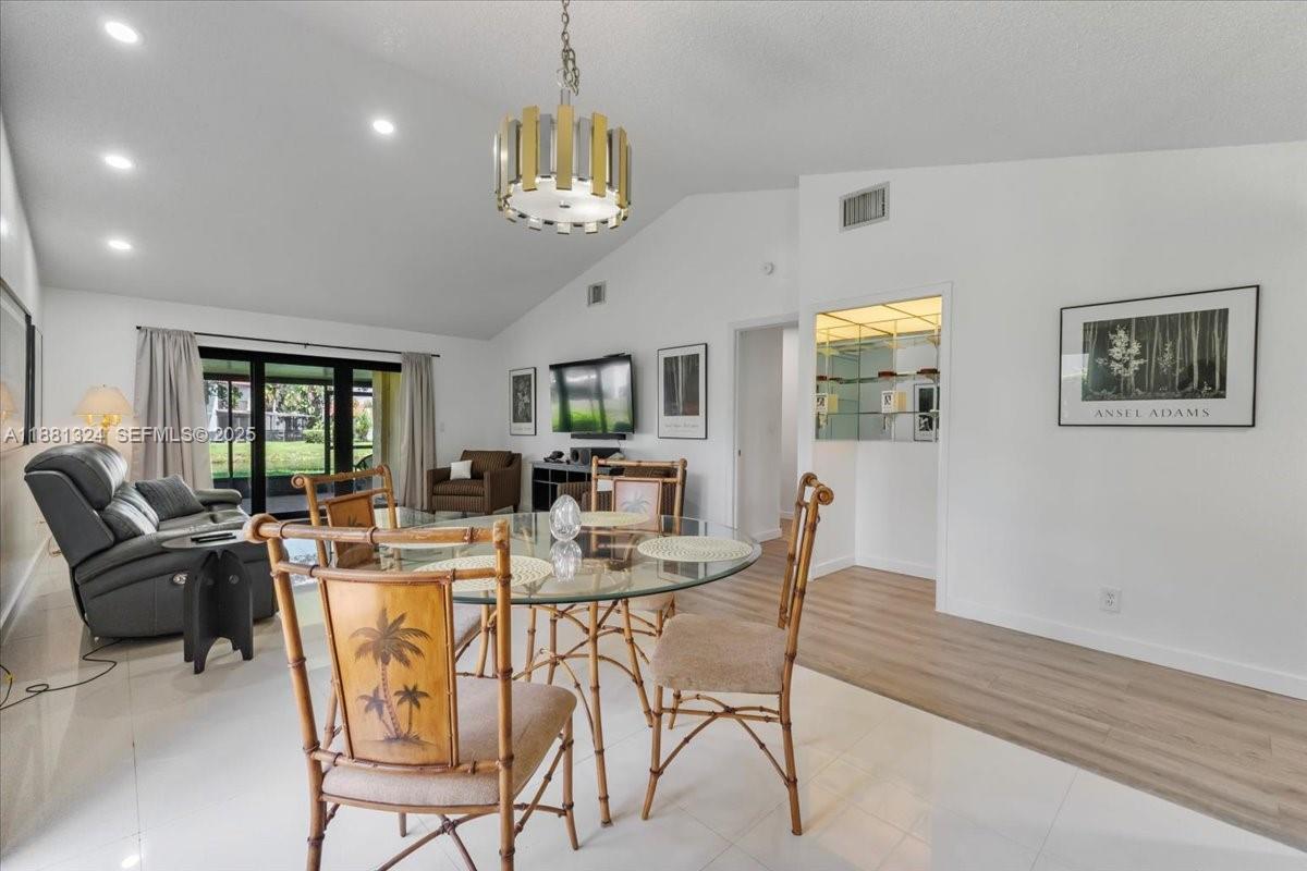 A dining area with a glass table and bamboo chairs sits before a living room — 16273 Laurel Dr # 7, Weston FL 33326, WESTON, FL