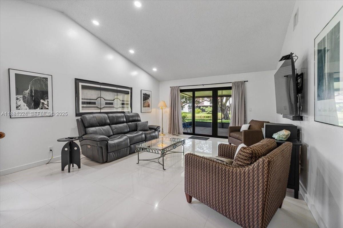 A living room features white tile floors, a dark leather sofa, and sliding glass doors — 16273 Laurel Dr # 7, Weston FL 33326, WESTON, FL