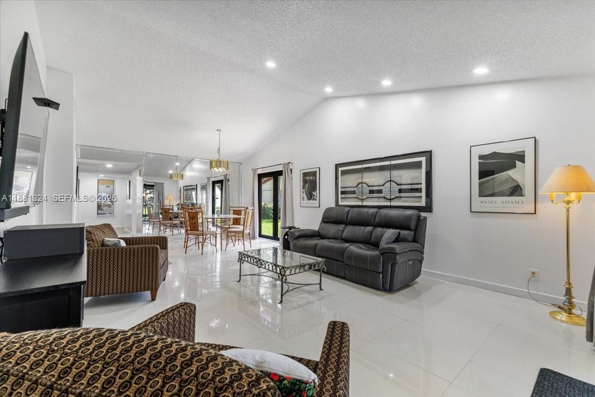 A living room features white tile floors, a vaulted ceiling, and a dark leather sofa — 16273 Laurel Dr # 7, Weston FL 33326, WESTON, FL