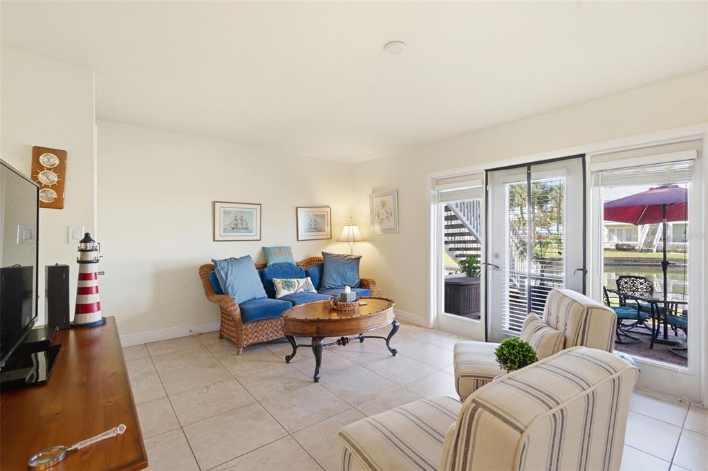 A living room features tile floors, a wicker sofa, striped armchairs, and a sliding door — 5191 SALMON DRIVE SE UNIT B, ST PETERSBURG, FL