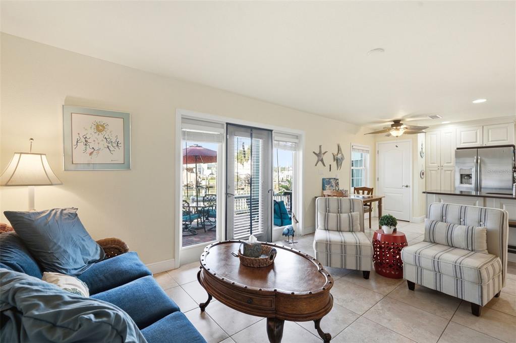 A living room with a blue sofa, striped armchairs, a coffee table, and patio access — 5191 SALMON DRIVE SE UNIT B, ST PETERSBURG, FL