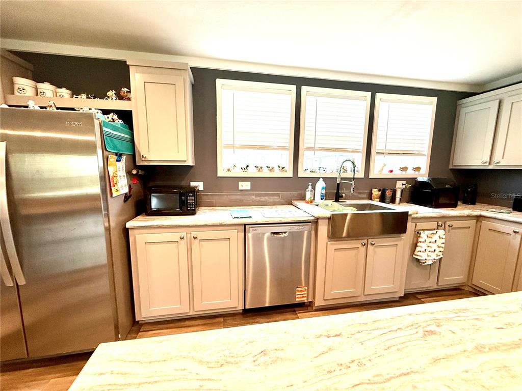 A kitchen features light-colored cabinets, stainless steel appliances, and a farmhouse sink — 7589 CR 763, BUSHNELL, FL