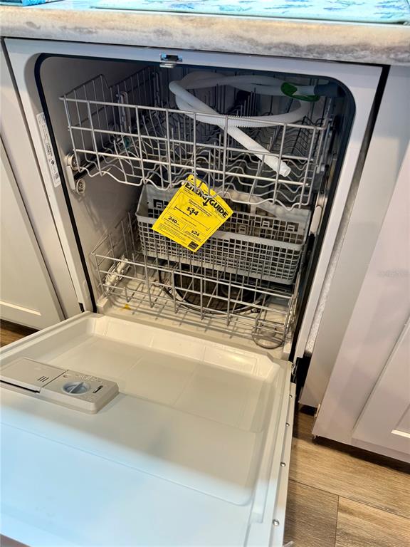An open dishwasher with racks and an EnergyGuide tag sits in a kitchen cabinet — 7589 CR 763, BUSHNELL, FL