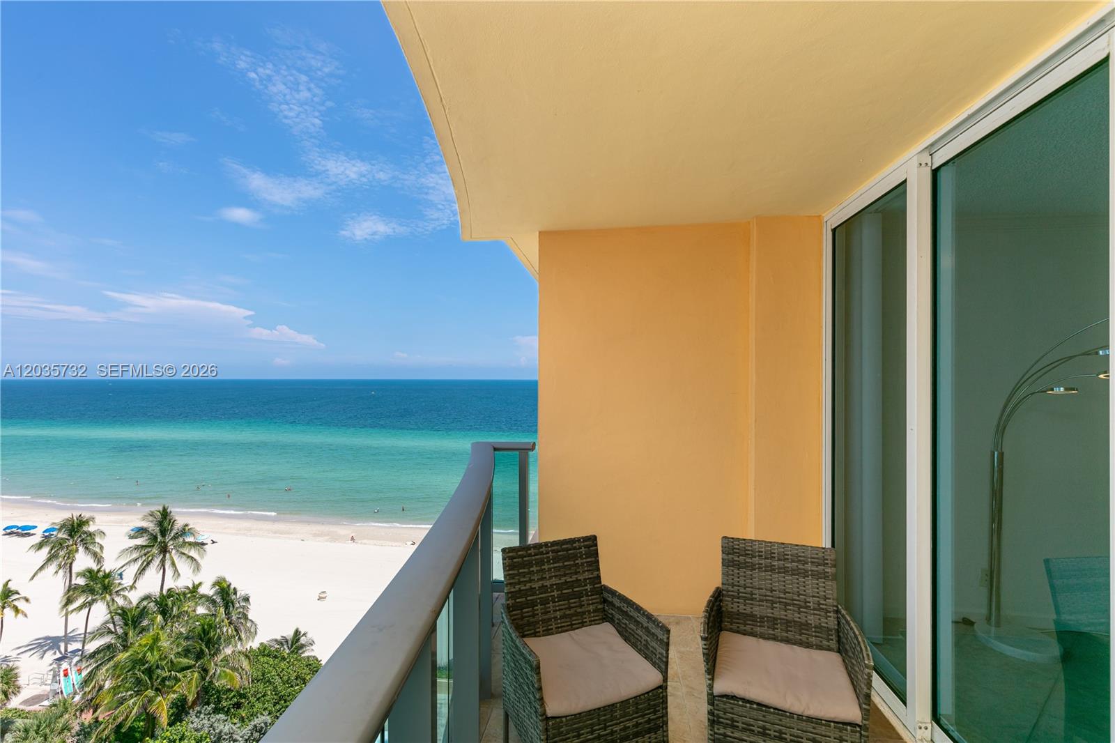 A balcony with two wicker chairs overlooks a sandy beach and the ocean — 2501 S Ocean Dr # 1008, Hollywood FL 33019, HOLLYWOOD, FL