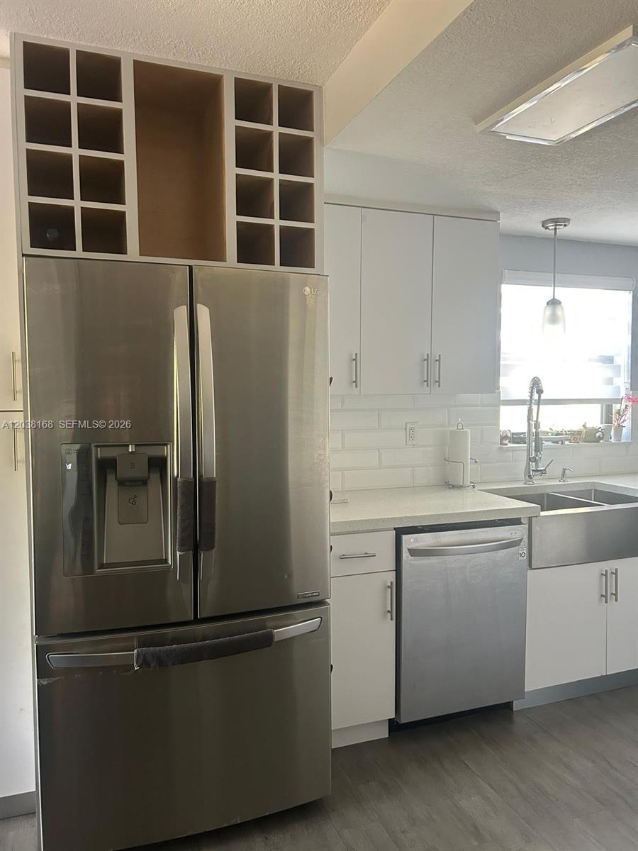 A kitchen features stainless steel appliances, white cabinets, a subway tile backsplash, and wine storage — 8820 SW 123rd Ct # L410, Miami FL 33186, MIAMI, FL