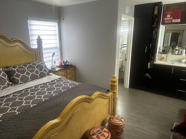 A bedroom features a wooden bed frame, a nightstand, and an adjacent bathroom vanity area — 8820 SW 123rd Ct # L410, Miami FL 33186, MIAMI, FL