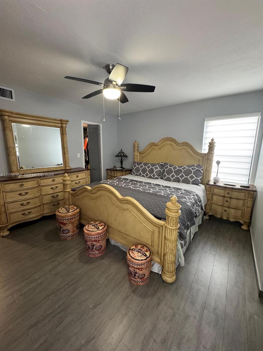 A bedroom features a wooden bed frame, matching dresser with mirror, and three cylindrical stools — 8820 SW 123rd Ct # L410, Miami FL 33186, MIAMI, FL