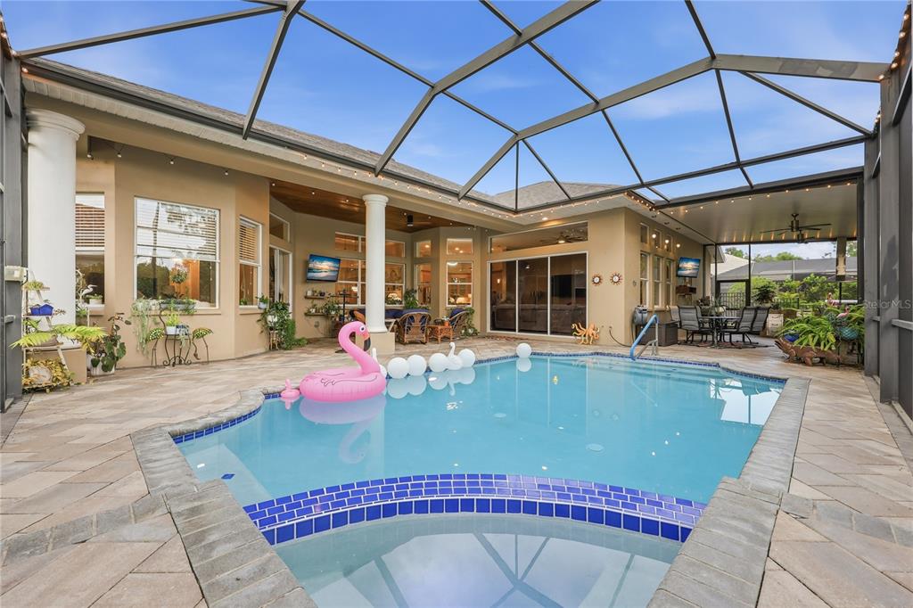 A screened-in patio features a swimming pool, a spa, and a covered outdoor seating area — 7049 TIMBER RIDGE WAY, LAND O LAKES, FL