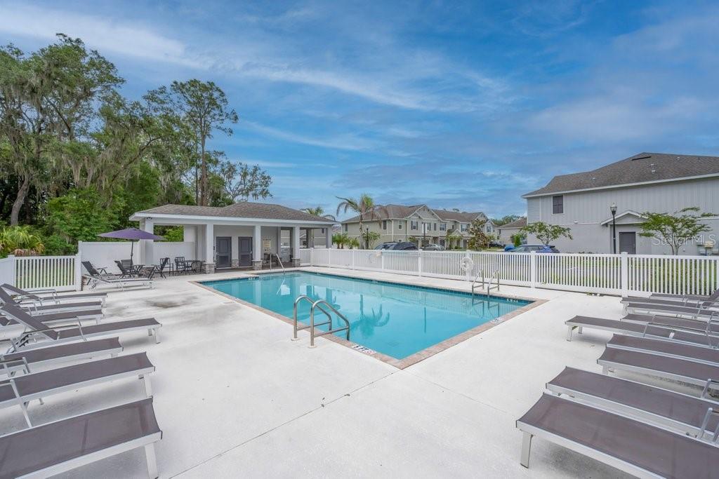 A rectangular swimming pool is surrounded by lounge chairs and a white fence — 10967 QUICKWATER COURT, RIVERVIEW, FL