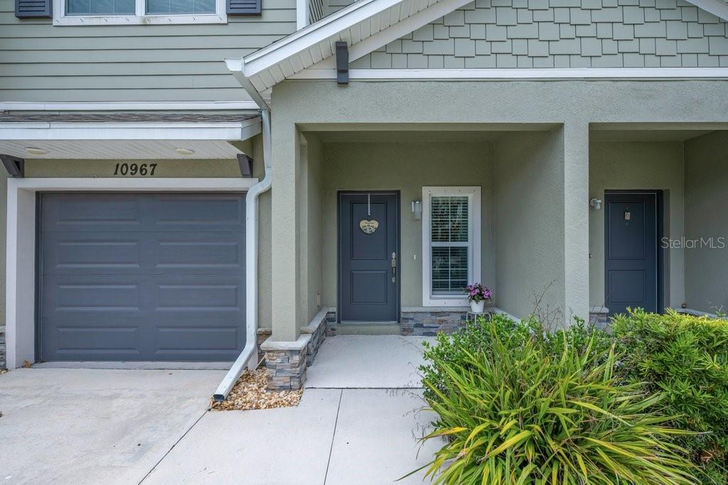 The exterior of a two-story townhouse features a gray garage, a covered entryway, and siding — 10967 QUICKWATER COURT, RIVERVIEW, FL