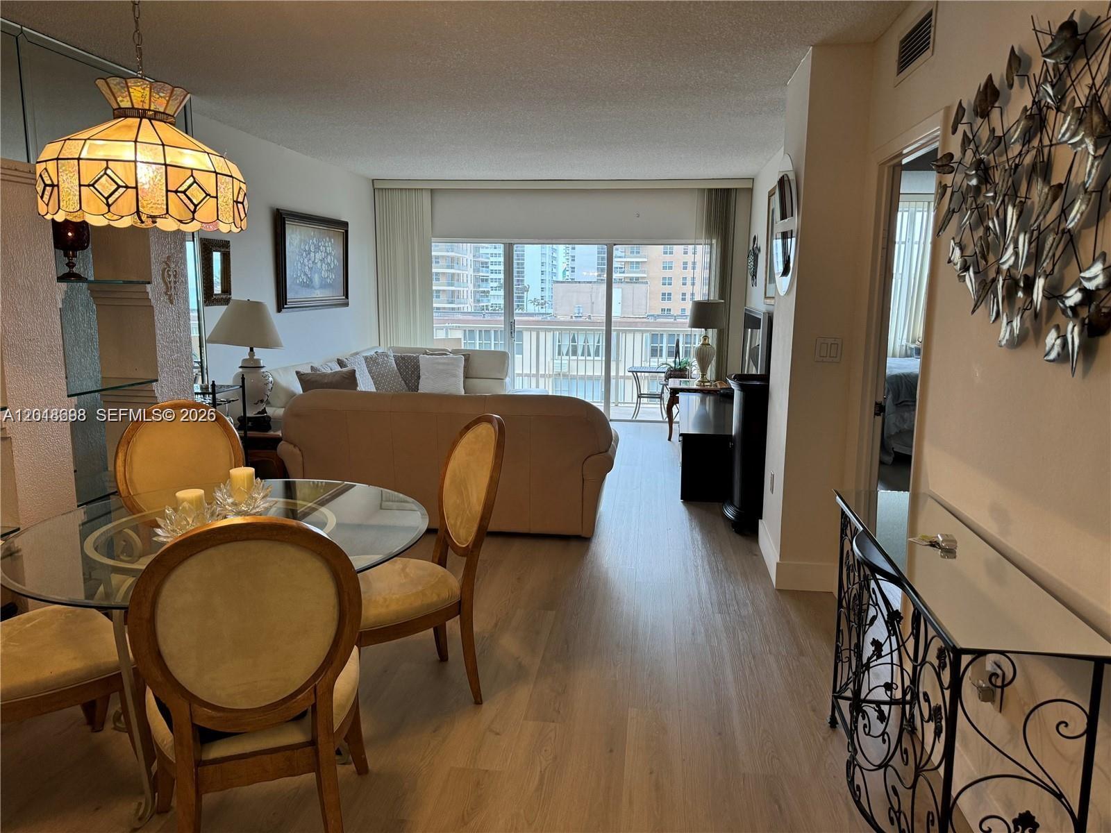 A dining area with a glass table leads into a living room with balcony access — 1950 S Ocean Dr # 4D, Hallandale Beach FL 33009, HALLANDALE BEACH, FL