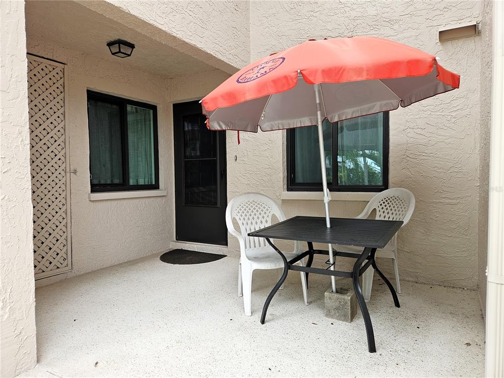A patio features a small table with an orange umbrella, two chairs, and a door — 1800 MARINER DRIVE UNIT 9, TARPON SPRINGS, FL