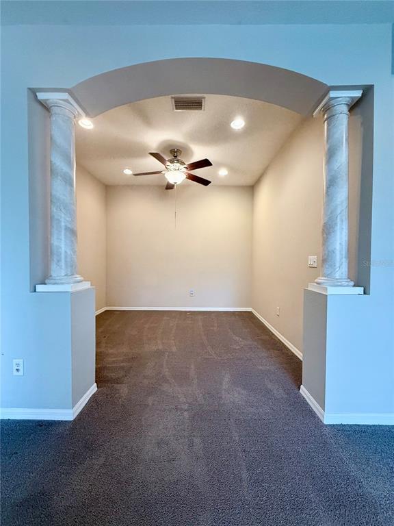 An arched entryway with decorative columns leads into a carpeted room with a ceiling fan — 3345 CHAPEL CREEK CIRCLE, WESLEY CHAPEL, FL