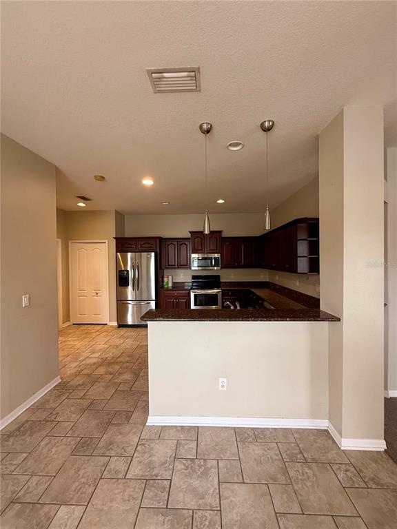 A kitchen features dark wood cabinets, stainless steel appliances, and a tiled floor — 3345 CHAPEL CREEK CIRCLE, WESLEY CHAPEL, FL